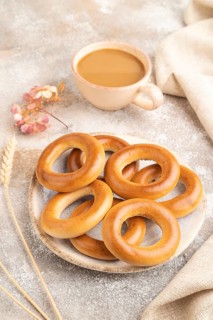 Homemade Ring Bagel with cup of coffee on brown concrete background and linen textile. side view,