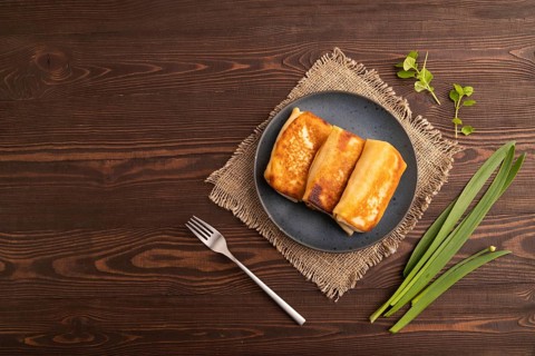 Fried crispy pancakes with meat and cheese on brown wooden background and linen textile. top view,