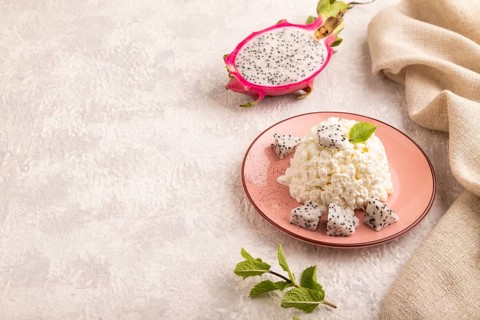 White ?ottage cheese, Curd, with Pithaya on gray concrete background and linen textile, side view,