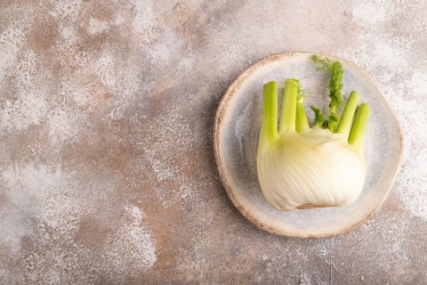 Fresh Fennel bulb on blue plate on brown concrete background, top view, flat lay, copy space,