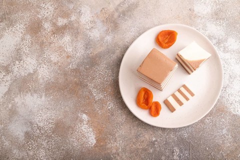Cocoa and milk jelly with dried apricots on brown concrete background, top view, flat lay, copy
