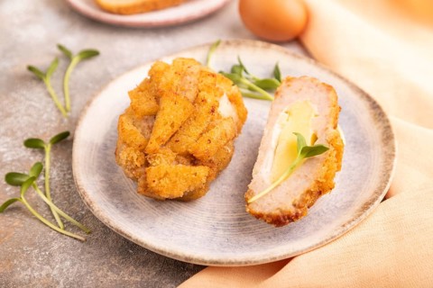 Chicken Schnitzel on blue plate with microgreen on brown concrete background and orange linen