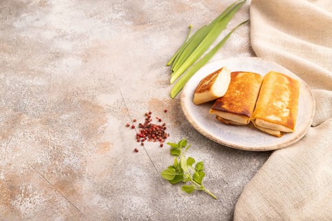 Fried crispy pancakes with meat and cheese on brown concrete background and linen textile. side