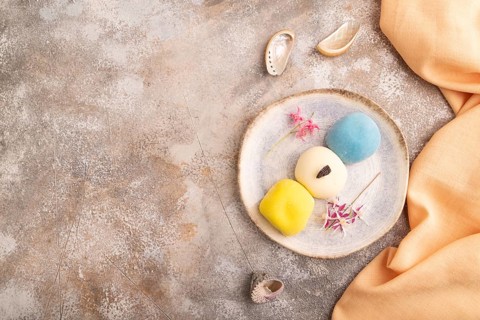 Japanese Mochi Cakes on brown concrete background and orange textile, top view, flat lay, copy