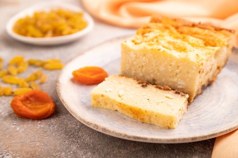 ?ottage cheese ?asserole, Curd cake, with dried apricots and raisins on brown concrete background