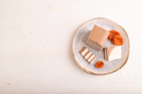 Cocoa and milk jelly with dried apricots on white wooden background, top view, flat lay, copy
