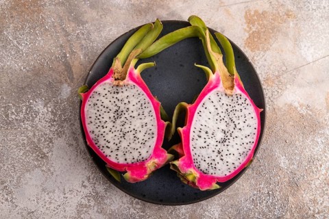 Ripe Pitaya on blue plate on brown concrete background, top view, flat lay, copy space, minimalism