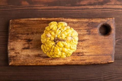 Decorative orange Pumpkin with tumors on cutting board on brown wooden background, top view, flat