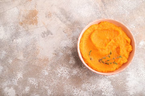 Sweet potato porridge in ceramic bowl on brown concrete background. Diet, healthy eating concept.