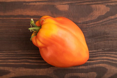 Red Heart Shape tomato on brown wooden background. Top view, flat lay, close up. healthy food,