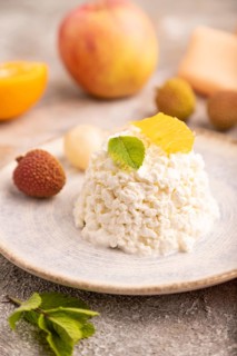White ?ottage cheese, Curd, with orange and lychee on brown concrete background and orange textile,