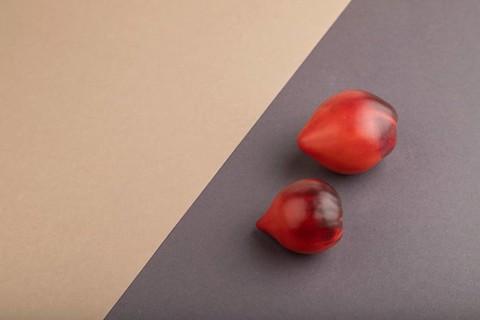Red Heart shape tomatoes on gray and beige pastel paper background. Side view, copy space. healthy