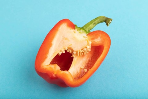 Red Cutted pepper on blue pastel background. Side view, copy space. Tropical, healthy food,