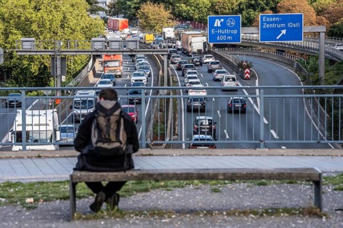 Man sitting on a bench, looking at the traffic jam on the A40 motorway, Ruhrschnellweg, in the city