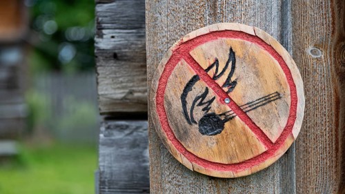 Brennendes Streichholz, kleine runde Holztafel mit aufgemaltem Verbotssymbol gegen das Entfachen