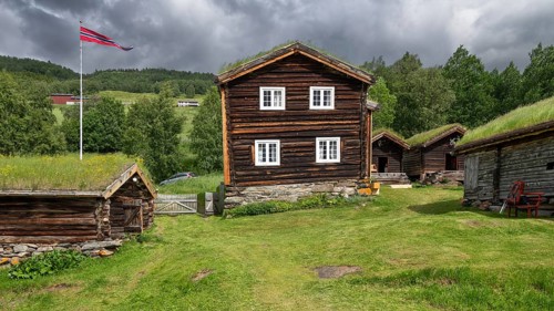 Norwegische Holzhäuser mit Gras auf den Dächern, Fahnenmast mit Norwegen-Flagge, historischer
