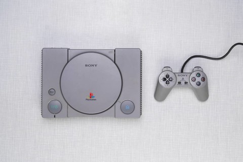 Top shot of a Playstation 1 with controller on a white Resopal board