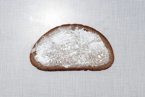 Top shot of a slice of bread smeared with margarine on a white Resopal plate