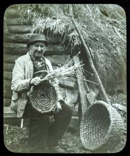 Portrait of elderly countryman weaving straw baskets in England, c 1890s-1900