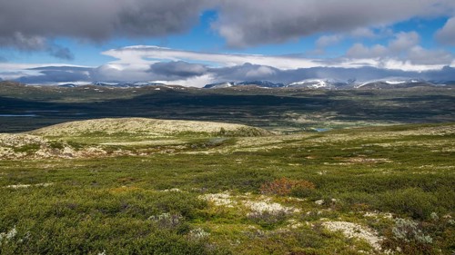 Weite, baumlose Gebirgslandschaft, tiefhängende Wolken und blauer Himmel, Pilgerweg Olavsweg,