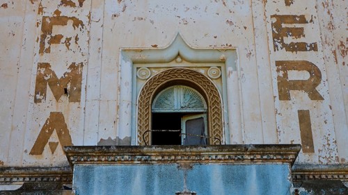Lost Place, Nahaufnahme der Fassade mit Bröckelstellen und verblassten Schriftzügen über einem