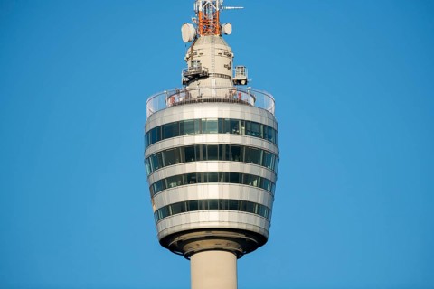 Architektonischer Fernsehturm mit Glas- und Metallelementen gegen blauen Himmel,