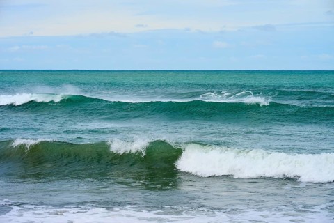 Türkisblaues Meer mit gleichmäßigen Wellen unter bewölktem Horizont, Kaka Point, Clutha District,