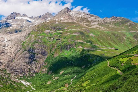 View of Furka pass road Alpine pass with tight bends hairpin bends on steep mountain slope above