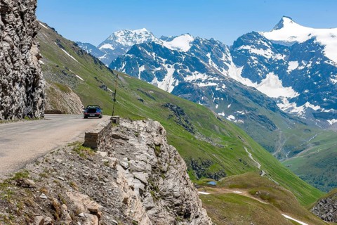 View of alpine road carved into rocky escarpment in high Alps near pass summit of highest asphalted