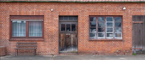 View of the entrance area of an older residential building with a red brick workshop, Uenzen,