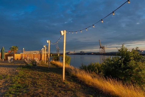 View from the outside area of a restaurant at Lankenauer Höft through a string of lights onto