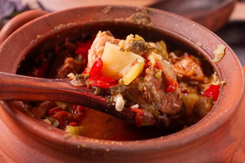 Chanakhi, a Georgian dish. in a clay pot, on a wooden table, stewed meat with vegetables, homemade,