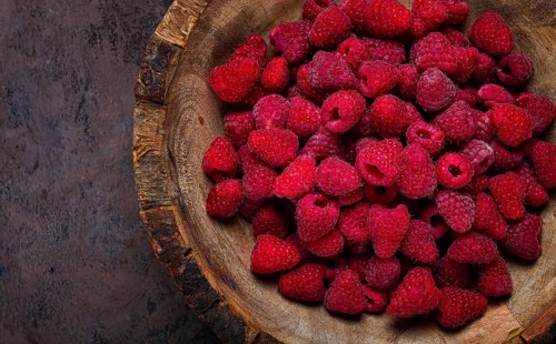 Fresh raspberries in a wooden bowl, food background, concept, food styling, on a dark table, top