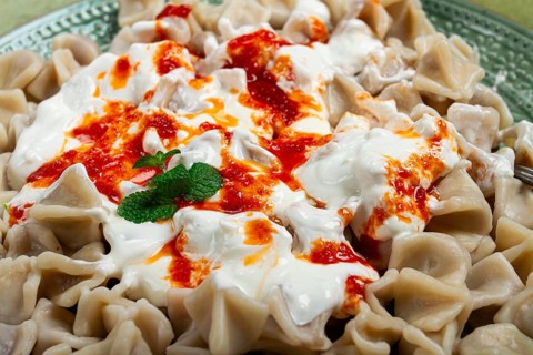 The dish features a generous serving of Turkish dumplings topped with velvety yogurt and a drizzle