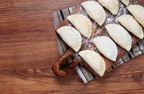 Traditional Polish dish, dumplings, raw, frozen, on a cutting board, wooden table, top view, no