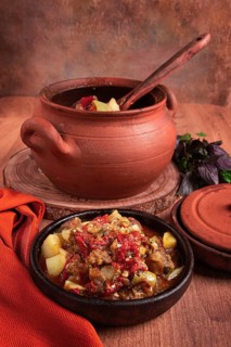Chanakhi, a Georgian dish. in a clay pot, on a wooden table, stewed meat with vegetables, homemade,