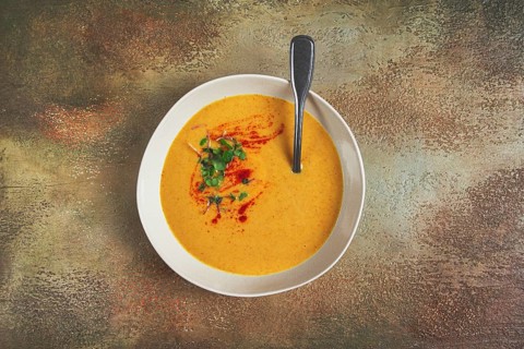 Pumpkin cream soup, in a white bowl on a textured background, top view, homemade, no people, rustic