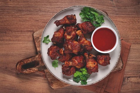 Juicy fried chicken pieces, served with spicy dipping sauce, on a rustic wooden table