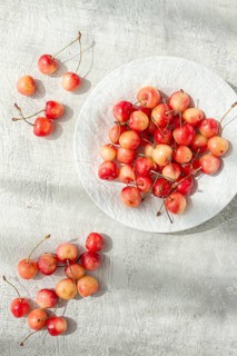 Yellow cherries on a white platter, scattered on the table, natural light, top view