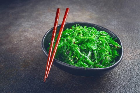 Chuka salad, made from fresh seaweed, with sesame dressing, served in a black bowl, with chopsticks