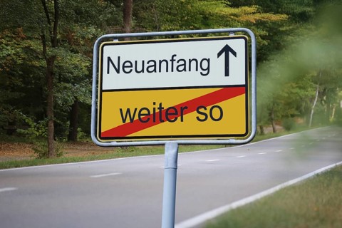 (Photomontage) An exit sign in front of a country road points in the direction of NEUANFANG and