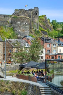 Tourists at restaurant along the river Ourthe and ruined castle in the city La Roche-en-Ardenne,