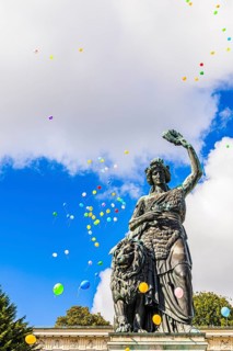 Colourful balloons rise high above the statue of Bavaria into the white-blue sky, grand finale of