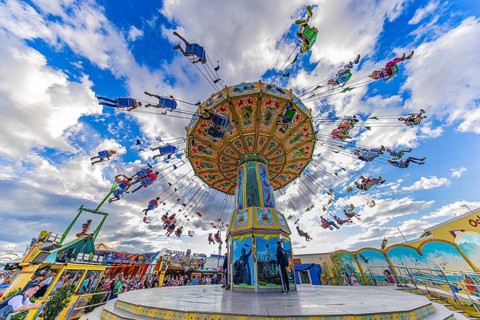Chain carousel in motion in front of a white-blue sky, Theresienwiese, Oktoberfest, Munich, Upper