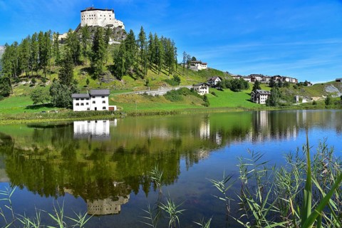 Tarasp Castle in the Lower Engadine is reflected in Lake Tarasp, Graubünden, Switzerland