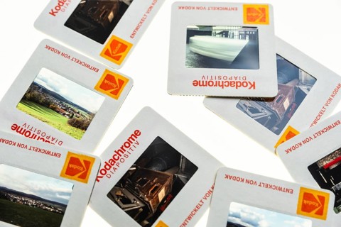 Many framed Kodachrome slides on a light table with magnifying glass, top shot