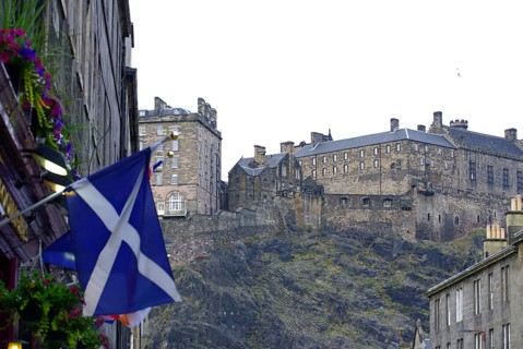 Scottish castle on a hill surrounded by buildings and a Scottish flag, Old Town, Edinburgh,
