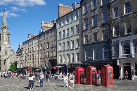 Lively street view with historic buildings and striking red telephone boxes in daylight, Royal