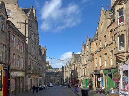 Historic street lined with old buildings under a clear sky, Old Town, Edinburgh, Scotland, United