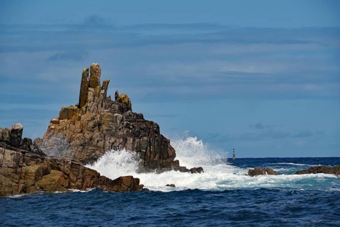 Rough sea with waves crashing against rocks under a blue sky, Isles of Scilly, Cornwall, Great